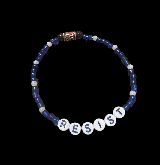 Blue beaded bracelet with white block letters spelling “RESIST”; handmade stretch-fit design symbolizing resistance to Trump, MAGA, and authoritarianism.